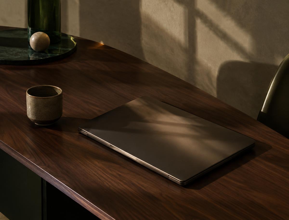 Closed laptop on a walnut desk in window light